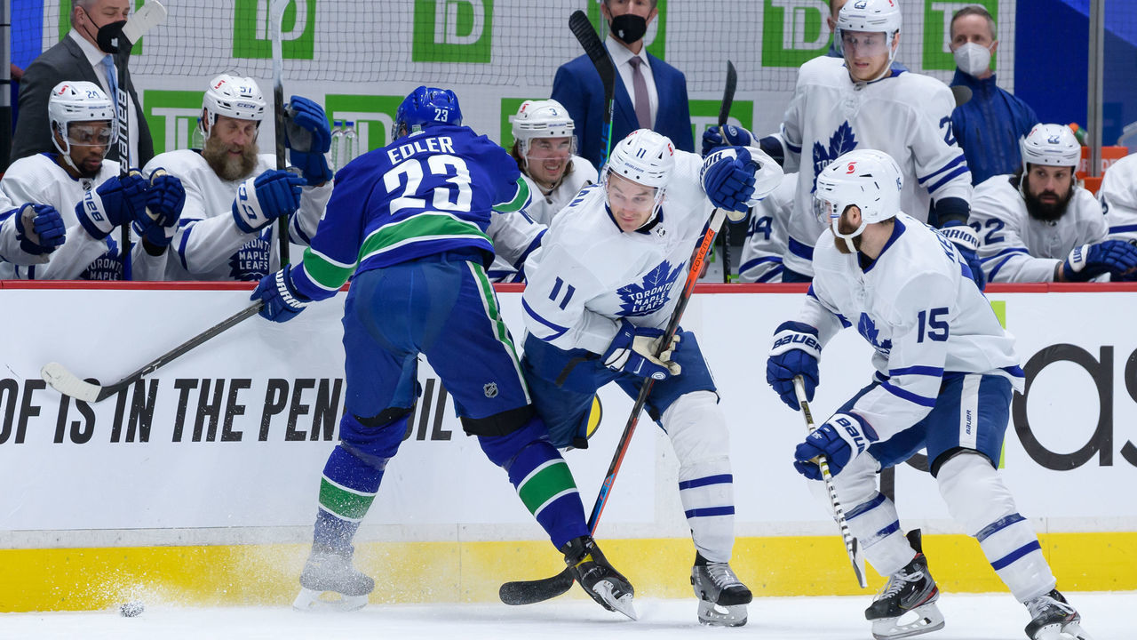 VANCOUVER, BC - APRIL 18: Toronto Maple Leafs left wing Zach Hyman (11) is kneed by Vancouver Canucks defenseman Alexander Edler (23) during their NHL game at Rogers Arena on April 18, 2021 in Vancouver, British Columbia, Canada.