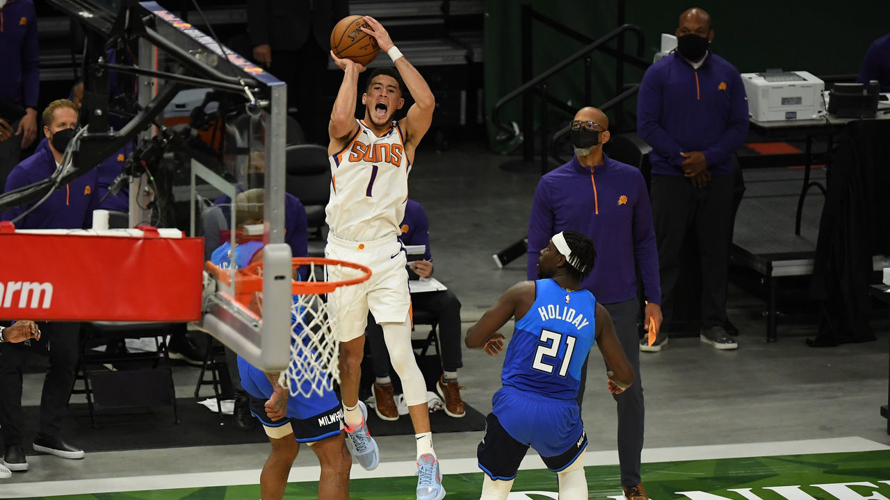 MILWAUKEE, WISCONSIN - APRIL 19: Devin Booker #1 of the Phoenix Suns is fouled by Jrue Holiday #21 of the Milwaukee Bucks as he attempts the game winning shot in overtime at Fiserv Forum on April 19, 2021 in Milwaukee, Wisconsin.