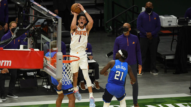 MILWAUKEE, WISCONSIN - APRIL 19: Devin Booker #1 of the Phoenix Suns is fouled by Jrue Holiday #21 of the Milwaukee Bucks as he attempts the game winning shot in overtime at Fiserv Forum on April 19, 2021 in Milwaukee, Wisconsin.