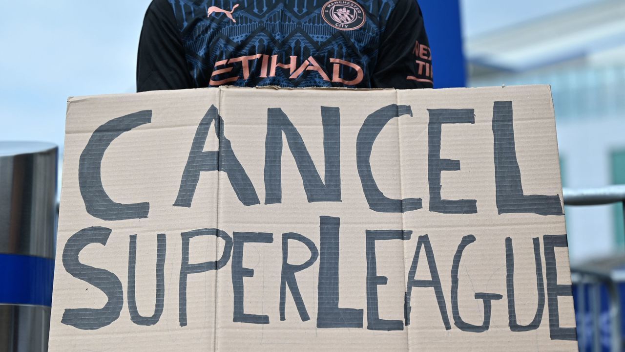 A supporter wearing a Manchester City shirt holds up a placard critical of the idea of a New European Super League, outside English Premier League club Chelsea's Stamford Bridge stadium in London on April 20, 2021, ahead of their game against Brighton. - The 14 Premier League clubs not involved in the proposed European Super League "unanimously and vigorously rejected" the plans at an emergency meeting on Tuesday. Liverpool, Arsenal, Chelsea, Manchester City, Manchester United and Tottenham Hotspur are the English clubs involved.