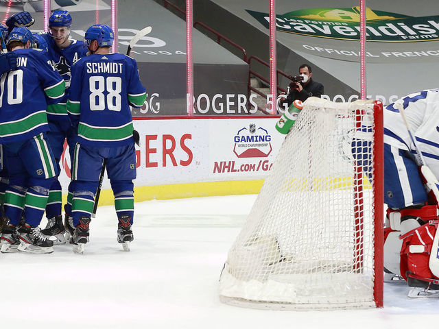 VANCOUVER, BC - APRIL 20: David Rittich #33 of the Toronto Maple Leafs looks on dejected as Tanner Pearson #70 of the Vancouver Canucks is congratulated by teammates after scoring during their NHL game at Rogers Arena on April 20, 2021 in Vancouver, British Columbia, Canada.
