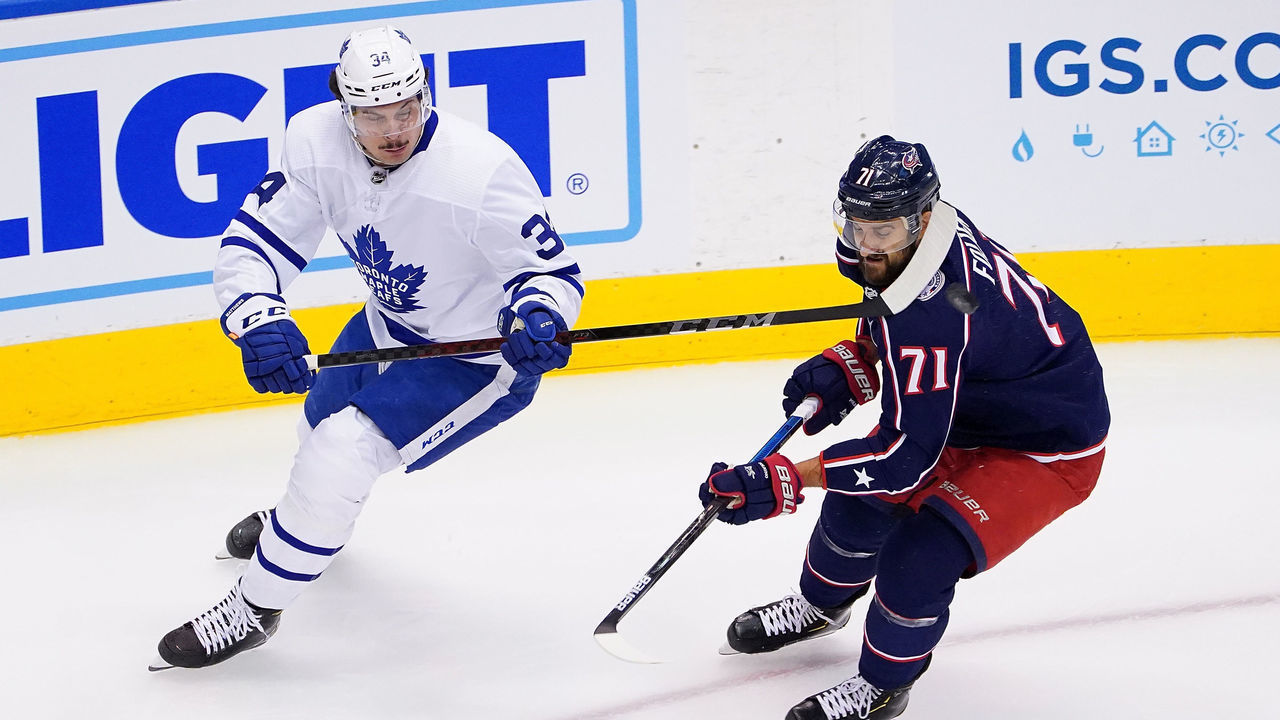 TORONTO, ONTARIO - AUGUST 07: Auston Matthews #34 of the Toronto Maple Leafs flips the puck past Nick Foligno #71 of the Columbus Blue Jackets in Game Four of the Eastern Conference Qualification Round prior to the 2020 NHL Stanley Cup Playoffs at Scotiabank Arena on August 07, 2020 in Toronto, Ontario.
