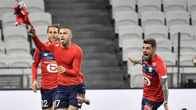 Lille's Turkish forward Burak Yilmaz (C) is congratuled by teammates after scoring during the French Ligue 1 football match between Olympique Lyonnais and LOSC Lille at the Groupama Stadium in Decines-Charpieu near Lyon, south-central France on April 25, 2021.