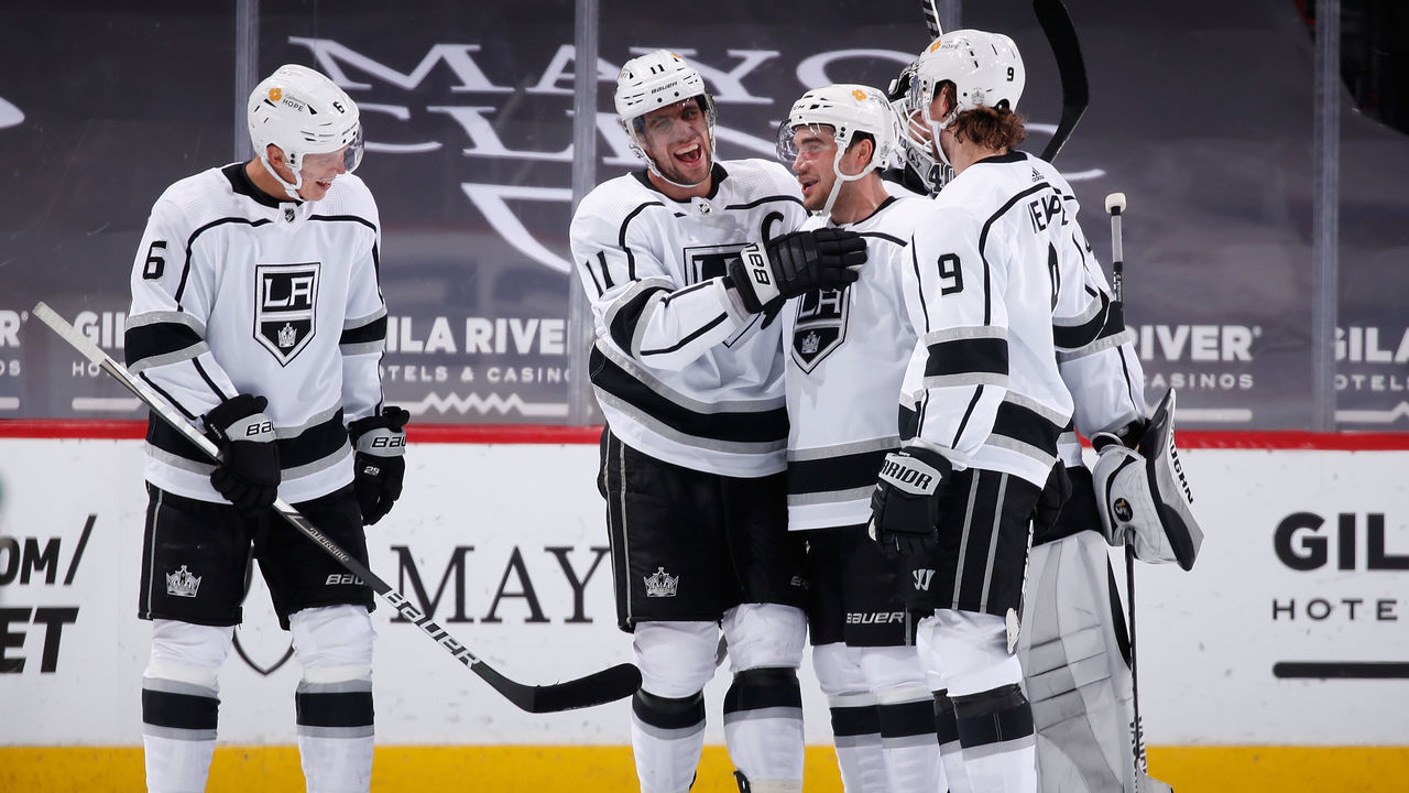 GLENDALE, ARIZONA - MAY 05: Anze Kopitar #11 of the Los Angeles Kings is congratulated by Olli Maatta #6, Sean Walker #26, goaltender Calvin Petersen #40 and Adrian Kempe #9 for recording his 1,000th career point after assisting on an empty-net goal against the Arizona Coyotes during the third period of the NHL game at Gila River Arena on May 05, 2021 in Glendale, Arizona. The Kings defeated the Coyotes 4-2.
