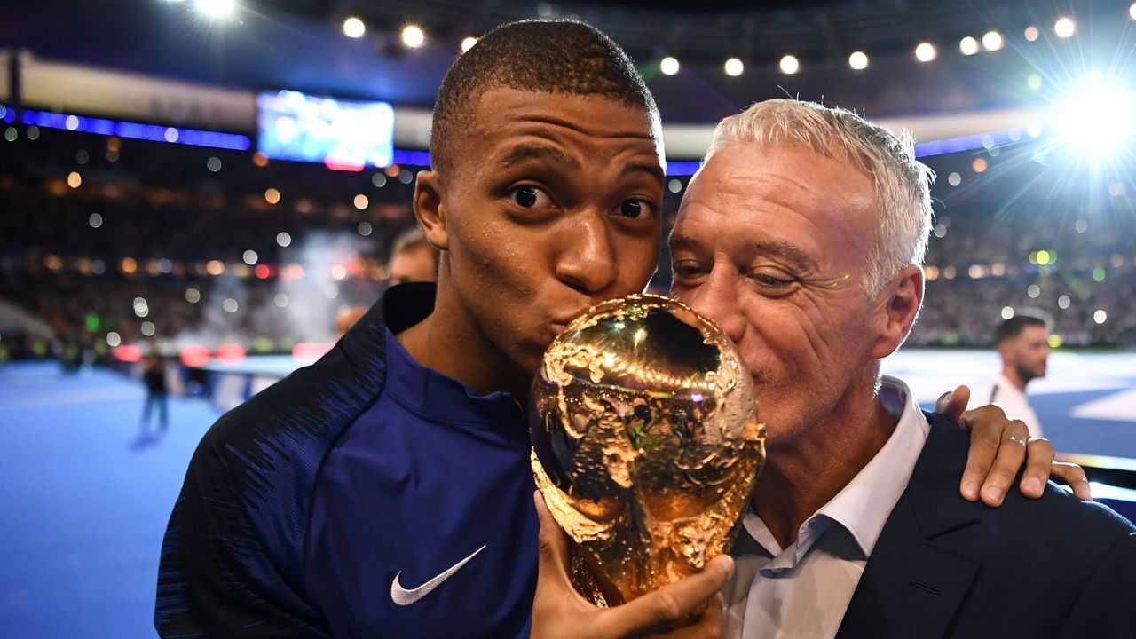 TOPSHOT - France's midfielder Kylian Mbappe (L) and France's coach Didier Deschamps kiss the 2018 World Cup trophy as they celebrate during a ceremony for the victory of the 2018 World Cup at the end of the UEFA Nations League football match between France and Netherlands at the Stade de France stadium, in Saint-Denis, northern of Paris, on September 9, 2018.