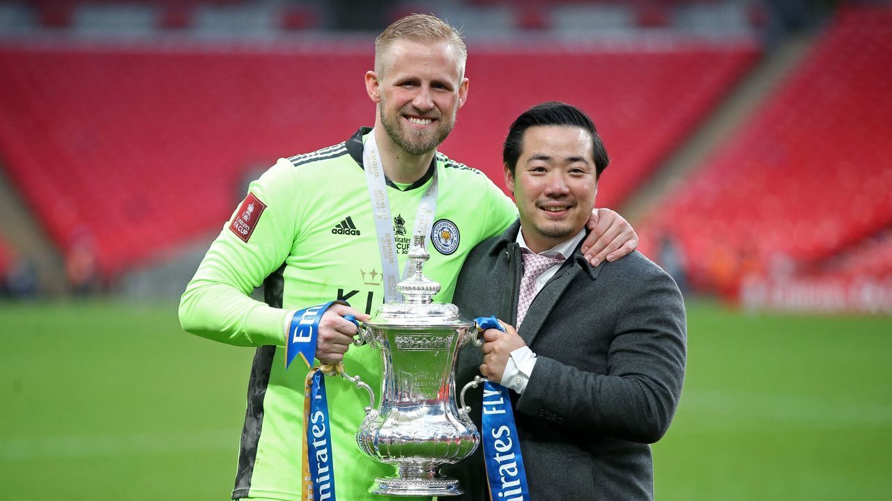 Leicester City's chairman Aiyawatt Srivaddhanaprabha (R) and Leicester City's Danish goalkeeper Kasper Schmeichel (L) hold the winner's trophy as the Leicester players celebrate victory after the English FA Cup final football match between Chelsea and Leicester City at Wembley Stadium in north west London on May 15, 2021. - Leicester won the FA Cup for the first time in the club's 137-year history as Youri Tielemans's sensational strike beat Chelsea 1-0 in front of 22,000 fans at Wembley. - NOT FOR MARKETING OR ADVERTISING USE / RESTRICTED TO EDITORIAL USE