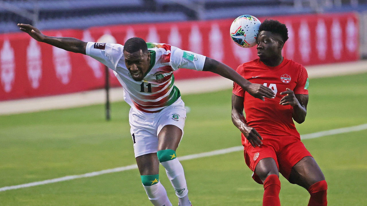 BRIDGEVIEW, ILLINOIS - JUNE 08: Alphonso Davies #19 of Canada heads the ball away from the ball Sheraldo Becker #11 of Suriname during a FIFA World Cup Qualifier at SeatGeek Stadium on June 08, 2021 in Bridgeview, Illinois.