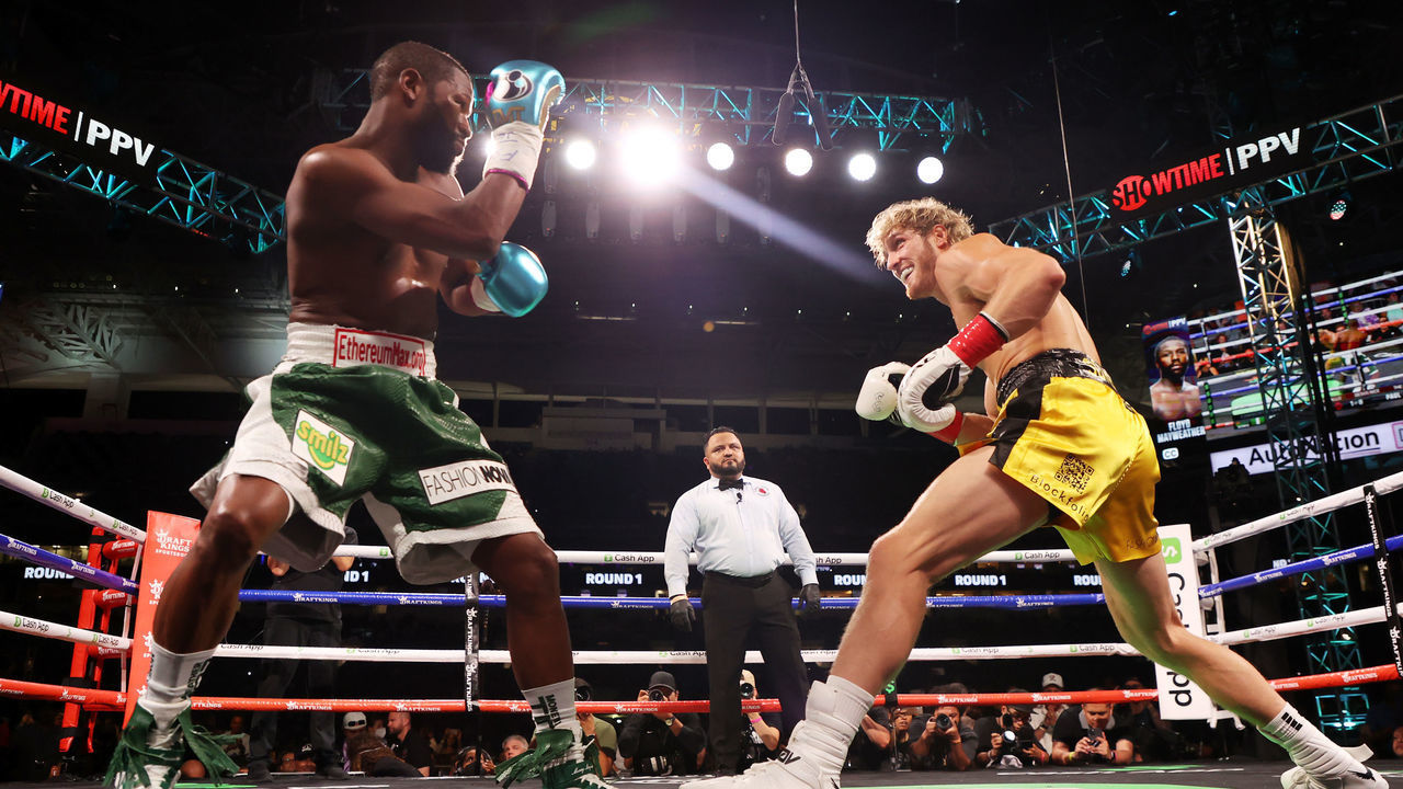 MIAMI GARDENS, FLORIDA - JUNE 06: Floyd Mayweather exchanges blows with Logan Paul (yellow shorts) during their contracted exhibition boxing match at Hard Rock Stadium on June 06, 2021 in Miami Gardens, Florida.