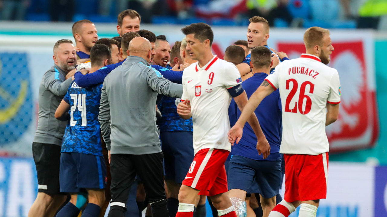 14 June 2021, Russia, St. Petersburg: Football: European Championship, Poland - Slovakia, preliminary round, Group E, matchday 1 at St Petersburg Stadium. Poland's Robert Lewandowski (front, l) and Poland's Tymoteusz Puchacz go past the Slovakia team celebrating their 1:2 win.Important: For editorial news reporting purposes only. Not used for commercial or marketing purposes without prior written approval of UEFA. Images must appear as still images and must not emulate match action video footage. Photographs published in online publications (whether via the Internet or otherwise) shall have an interval of at least 20 seconds between the posting. Photo: Igor Russak/dpa