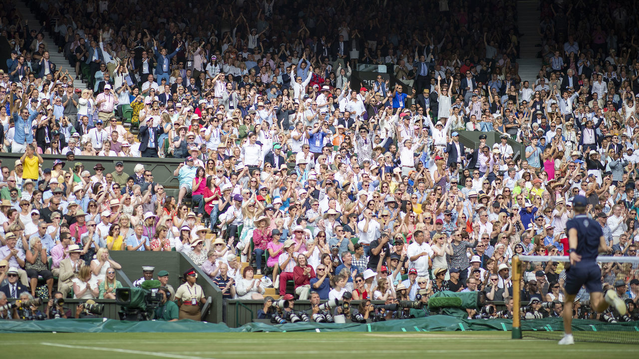LONDON, ENGLAND - July 14: Fans cheer Roger Federer of Switzerland in action against Novak Djokovic of Serbia during the Men's Singles Final on Centre Court during the Wimbledon Lawn Tennis Championships at the All England Lawn Tennis and Croquet Club at Wimbledon on July 14, 2019 in London, England.