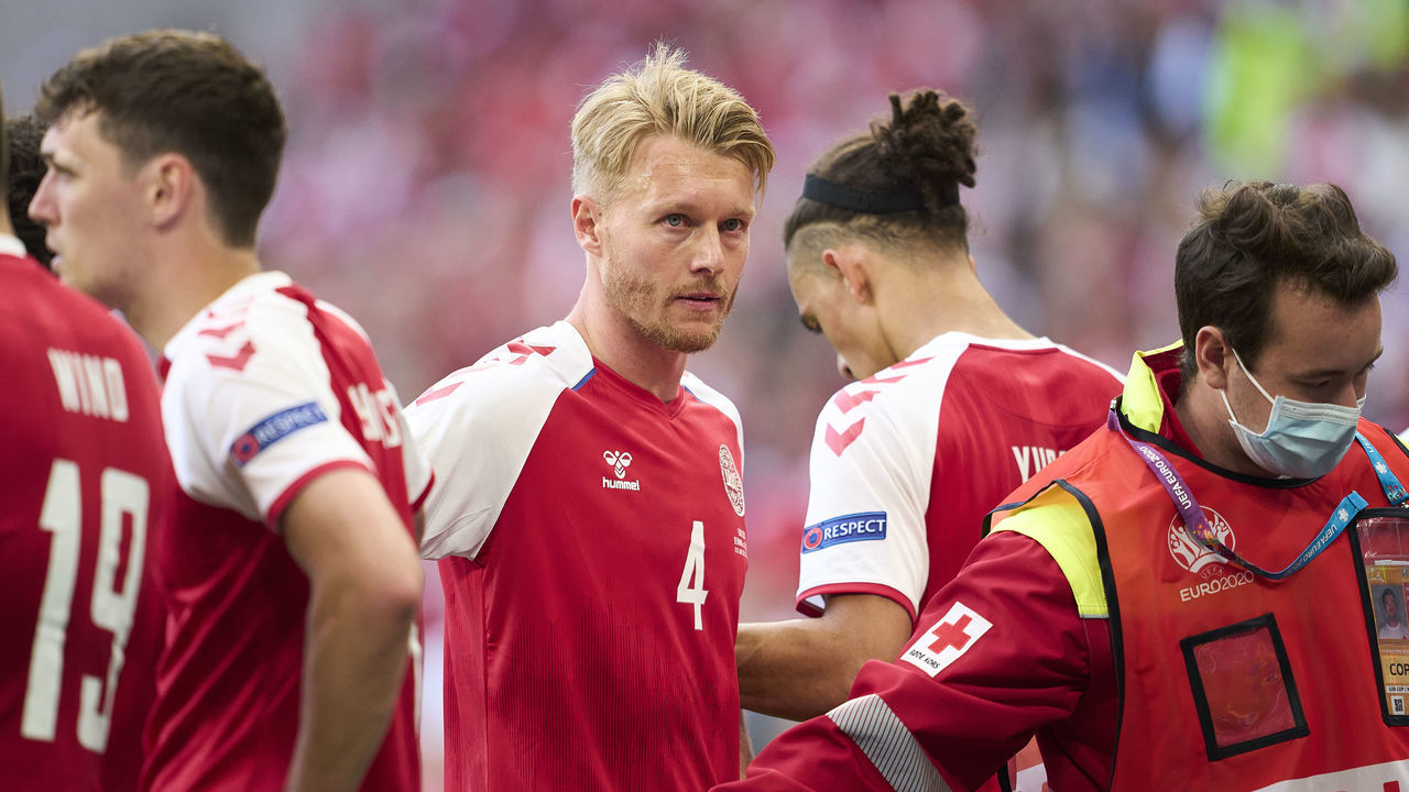COPENHAGEN, DENMARK - JUNE 12: Danish captain Simon Kjar of Denmark stands near Christian Eriksen of Denmark when he receives medical treatment during the UEFA EURO 2020 Group B match between Denmark and Finland at Parken Stadium on June 12, 2021 in Copenhagen, Denmark.