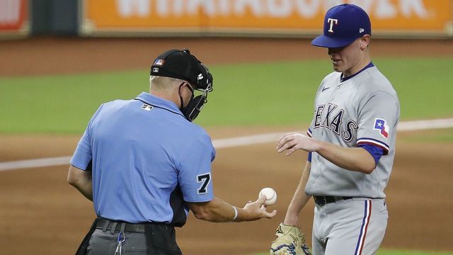 HOUSTON, TEXAS - SEPTEMBER 02: Home plate umpire Mike Muchlinski #76 checks the ball before giving it back to Kolby Allard #39 of the Texas Rangers in the third inning at Minute Maid Park on September 02, 2020 in Houston, Texas.