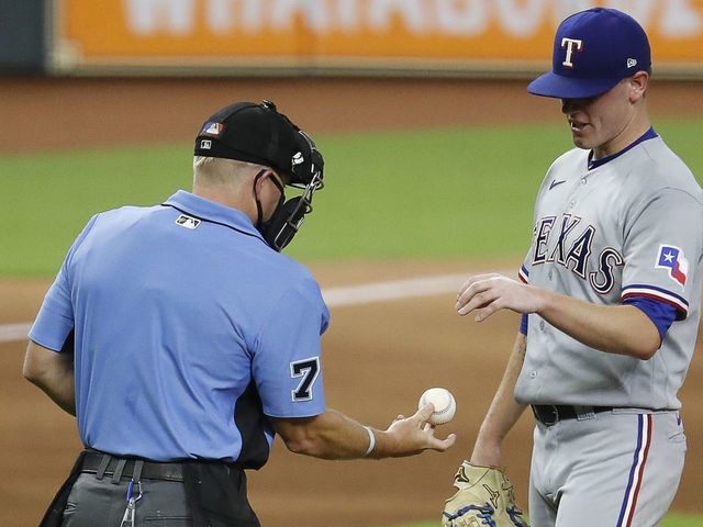 HOUSTON, TEXAS - SEPTEMBER 02: Home plate umpire Mike Muchlinski #76 checks the ball before giving it back to Kolby Allard #39 of the Texas Rangers in the third inning at Minute Maid Park on September 02, 2020 in Houston, Texas.