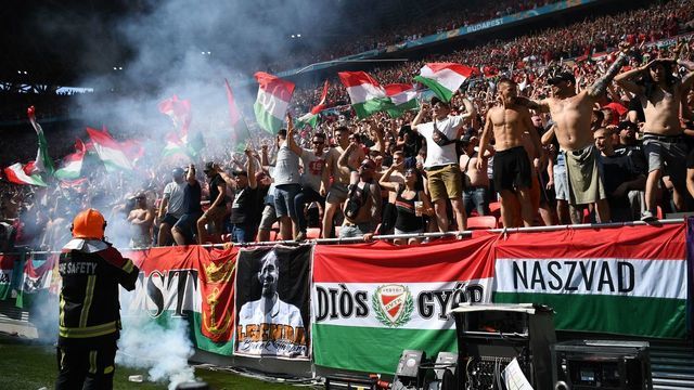 Members of the fire brigade arrive to deal with burning flares as Hungary fans celebrate scoring during the UEFA EURO 2020 Group F football match between Hungary and France at Puskas Arena in Budapest on June 19, 2021.