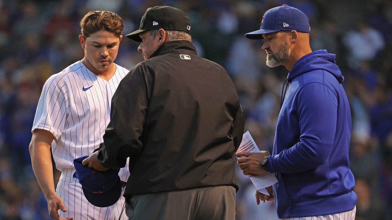 CHICAGO, ILLINOIS - JUNE 21: Umpire Hunter Wendelstedt examines the hat and glove of pitcher Keegan Thompson #71 of the Chicago Cubs as Cubs manager David Ross #22 watches at the end of the 5th inning against the Cleveland Indians at Wrigley Field on June 21, 2021 in Chicago, Illinois.