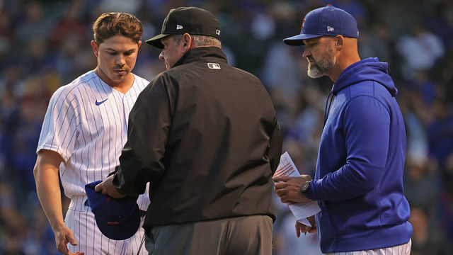 CHICAGO, ILLINOIS - JUNE 21: Umpire Hunter Wendelstedt examines the hat and glove of pitcher Keegan Thompson #71 of the Chicago Cubs as Cubs manager David Ross #22 watches at the end of the 5th inning against the Cleveland Indians at Wrigley Field on June 21, 2021 in Chicago, Illinois.