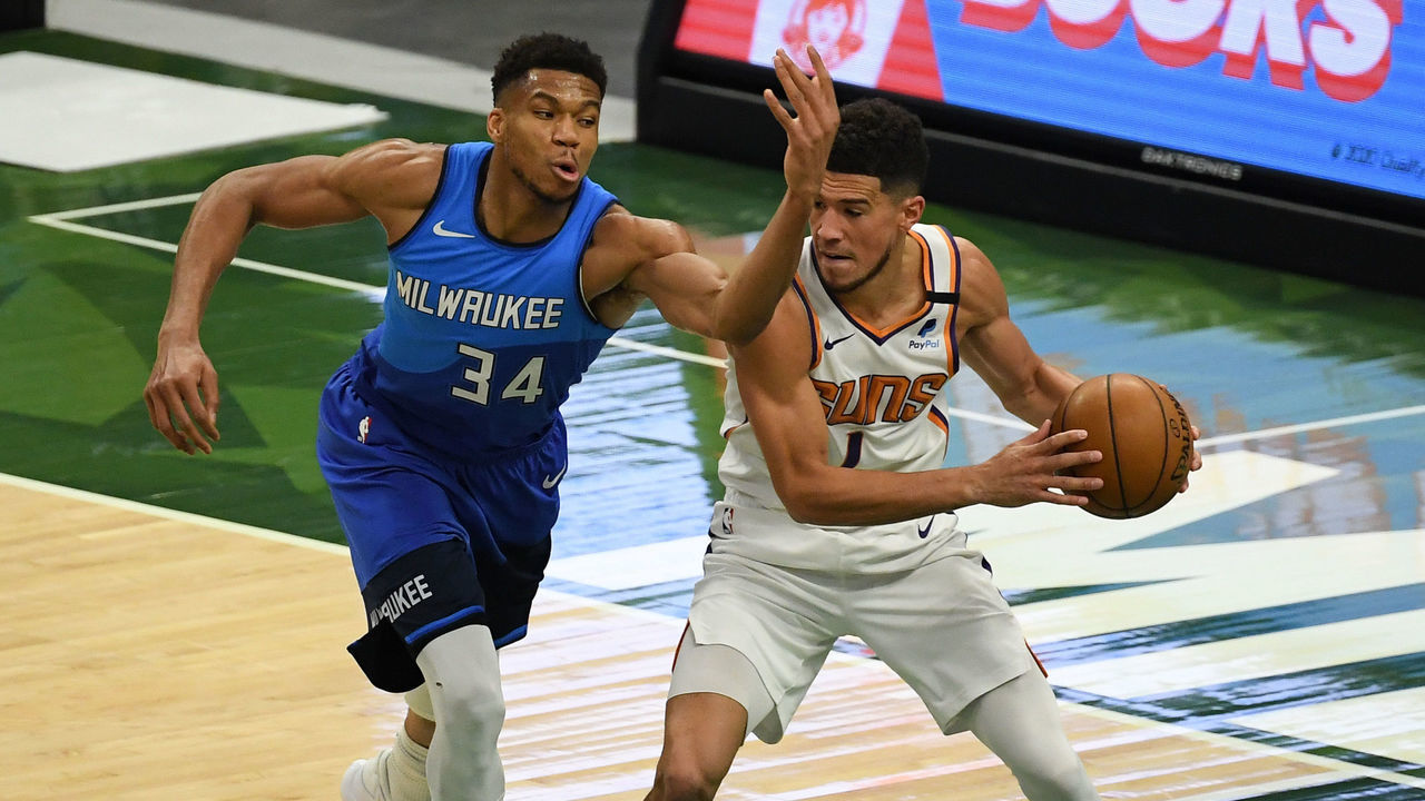 MILWAUKEE, WISCONSIN - APRIL 19: Giannis Antetokounmpo #34 of the Milwaukee Bucks attempts a steal against Devin Booker #1 of the Phoenix Suns in the third quarter at Fiserv Forum on April 19, 2021 in Milwaukee, Wisconsin.