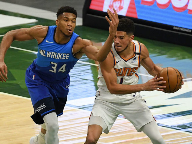 MILWAUKEE, WISCONSIN - APRIL 19: Giannis Antetokounmpo #34 of the Milwaukee Bucks attempts a steal against Devin Booker #1 of the Phoenix Suns in the third quarter at Fiserv Forum on April 19, 2021 in Milwaukee, Wisconsin.
