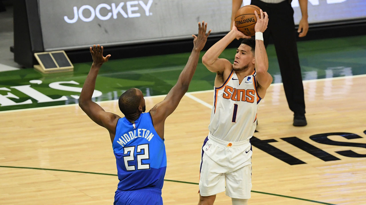 MILWAUKEE, WISCONSIN - APRIL 19: Devin Booker #1 of the Phoenix Suns takes a shot against Khris Middleton #22 of the Milwaukee Bucks in the third quarter at Fiserv Forum on April 19, 2021 in Milwaukee, Wisconsin.