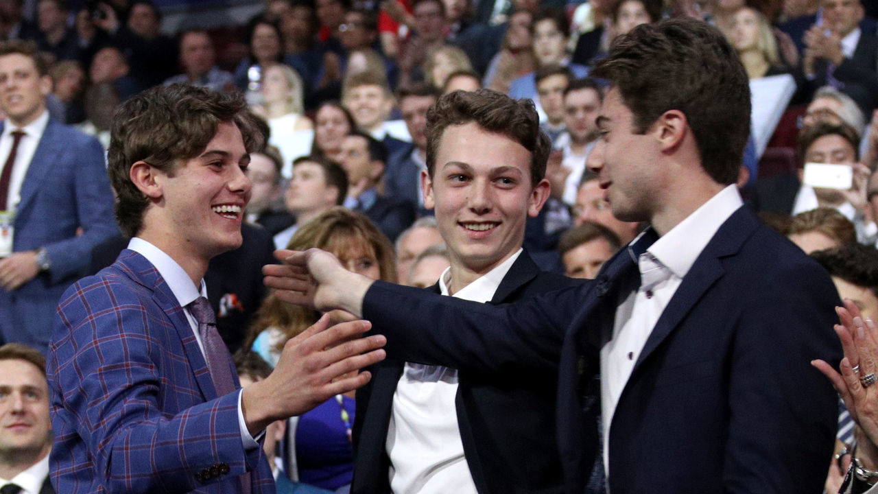 VANCOUVER, BRITISH COLUMBIA - JUNE 21: (L-R) Jack Hughes, first overall pick by the New Jersey Devils, is congratulated by his brothers Luke and Quinn Hughes during the first round of the 2019 NHL Draft at Rogers Arena on June 21, 2019 in Vancouver, Canada.
