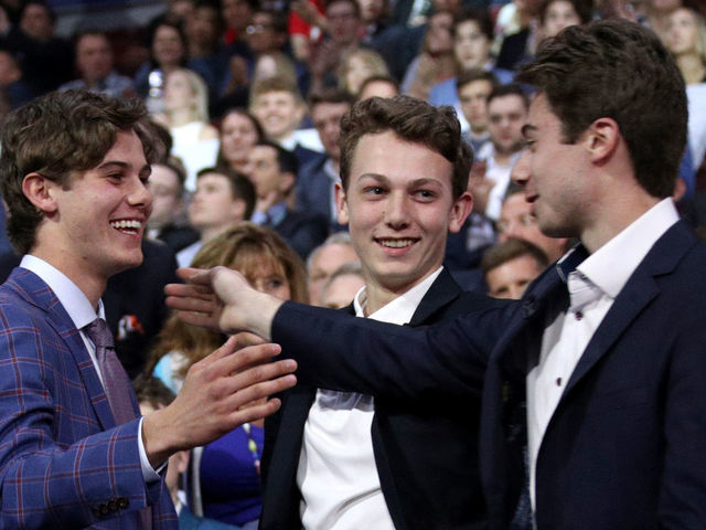 VANCOUVER, BRITISH COLUMBIA - JUNE 21: (L-R) Jack Hughes, first overall pick by the New Jersey Devils, is congratulated by his brothers Luke and Quinn Hughes during the first round of the 2019 NHL Draft at Rogers Arena on June 21, 2019 in Vancouver, Canada.