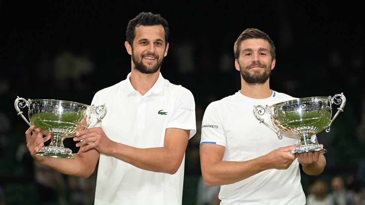 Croatia's Nikola Mektic (R) and Mate Pavic pose with the trophy after defeating Spain's Marcel Granollers and Argentina's Horacio Zeballos during their men's doubles final match on the twelfth day of the 2021 Wimbledon Championships at The All England Tennis Club in Wimbledon, southwest London, on July 10, 2021. - RESTRICTED TO EDITORIAL USE