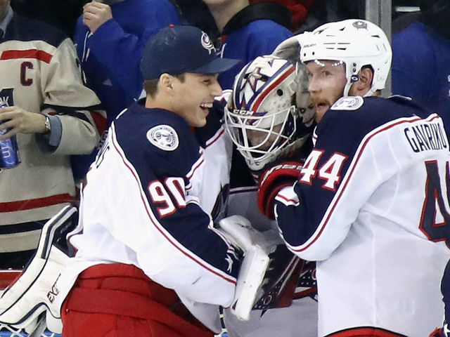 NEW YORK, NEW YORK - JANUARY 19: Fellow Latvia born goaltender Elvis Merzlikins #90 of the Columbus Blue Jackets reaches in to congratulate Matiss Kivlenieks #80 on his first NHL win in his first NHL game against the New York Rangers at Madison Square Garden on January 19, 2020 in New York City. The Blue Jackets defeated the Rangers 2-1.