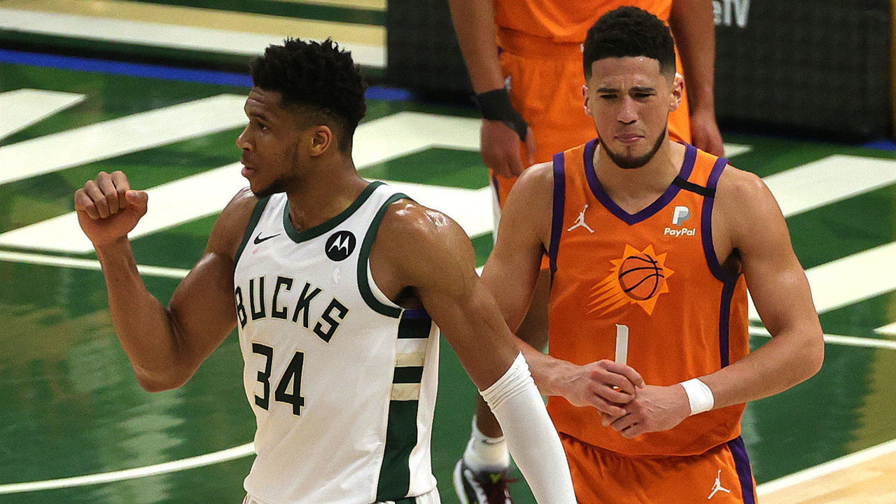 MILWAUKEE, WISCONSIN - JULY 14: Giannis Antetokounmpo #34 of the Milwaukee Bucks celebrates a win as Devin Booker #1 of the Phoenix Suns looks on in Game Four of the NBA Finals at Fiserv Forum on July 14, 2021 in Milwaukee, Wisconsin.