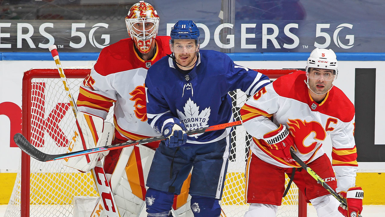 TORONTO, ON - APRIL 13: Zach Hyman #11 of the Toronto Maple Leafs works between Jacob Markstrom #25 and Mark Giordano #5 of the Calgary Flames during an NHL game at Scotiabank Arena on April 13, 2021 in Toronto, Ontario, Canada. The Flames defeated the Maple Leafs 3-2 in overtime.