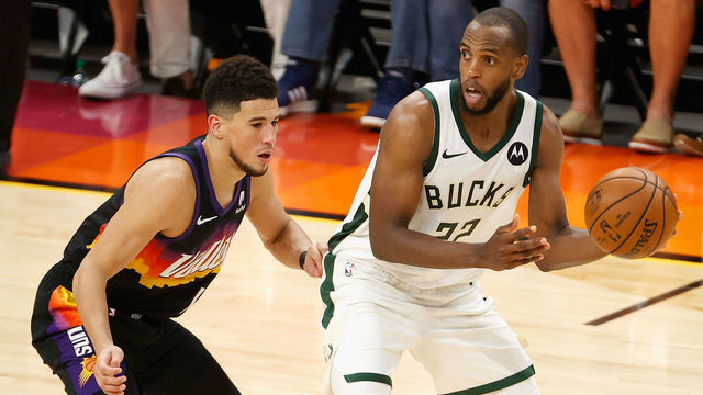 PHOENIX, ARIZONA - JULY 17: Khris Middleton #22 of the Milwaukee Bucks looks to pass around Devin Booker #1 of the Phoenix Suns in the second half of game five of the NBA Finals at Footprint Center on July 17, 2021 in Phoenix, Arizona. The Bucks defeated the Suns 123-119.