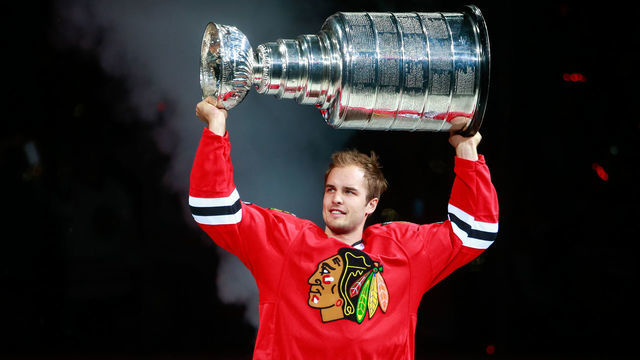 CHICAGO, IL - OCTOBER 07: Niklas Hjalmarsson #4 of the Chicago Blackhawks raises the Stanley Cup during pre-game ceremonies of the the season opener against the New York Rangers during an NHL game at the United Center on October 7, 2015 in Chicago, Illinois.