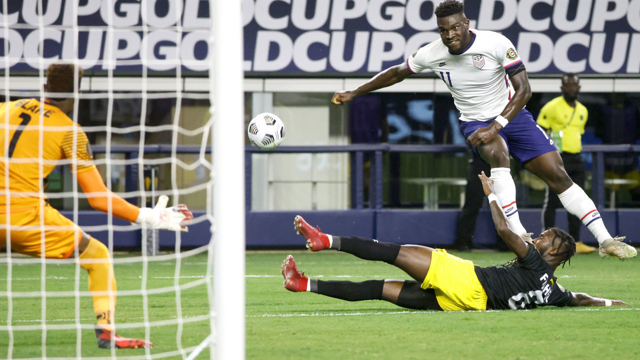 ARLINGTON, TEXAS - JULY 25: Daryl Dike #11 of the United States takes a shot at goal as Andre Blake #1 of Jamaica and teammate Oniel Fisher #8 defend in the first half of a 2021 CONCACAF Gold Cup Quarterfinals match at AT&T Stadium on July 25, 2021 in Arlington, Texas.