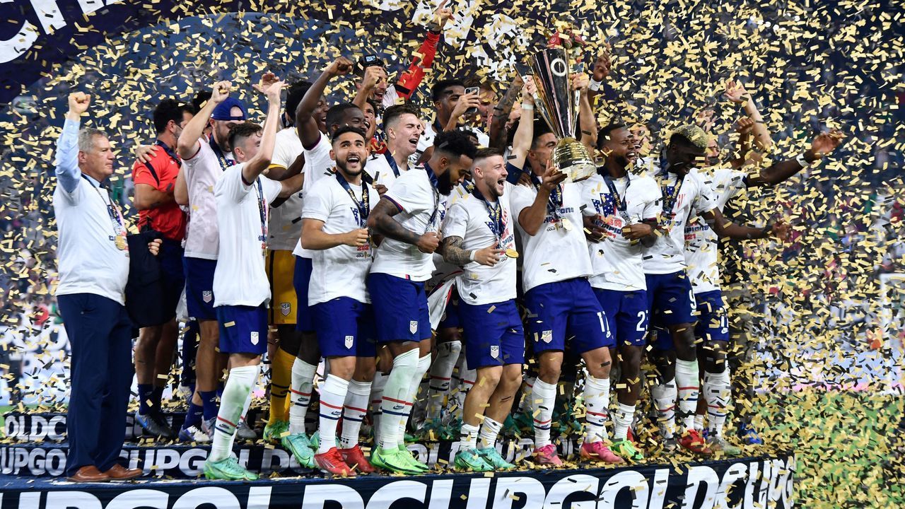 USA players hold the Concacaf Gold Cup and celebrate on the podium after winning the final football match against Mexico at the Allegiant stadium in Las Vegas, Nevada on August 1, 2021.
