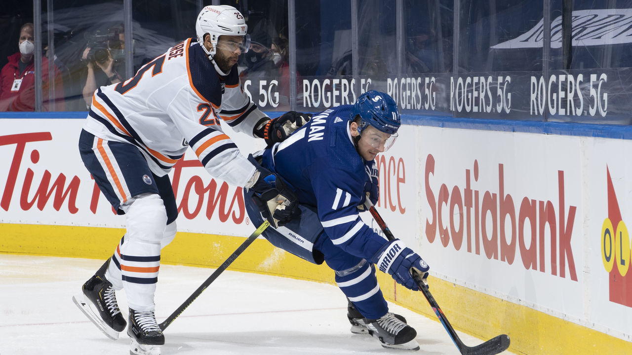 TORONTO, ON - MARCH 27: Zach Hyman #11 of the Toronto Maple Leafs plays the puck against Darnell Nurse #25 of the Edmonton Oilers during the third period at the Scotiabank Arena on March 27, 2021 in Toronto, Ontario, Canada.