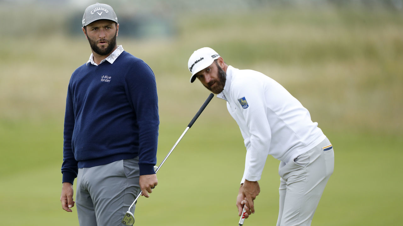 SANDWICH, ENGLAND - JULY 14: Dustin Johnson of the United States plays a shot on the green of the fifth hole as Jon Rahm of Spain looks on during a practice round ahead of The 149th Open at Royal St George’s Golf Club on July 14, 2021 in Sandwich, England.