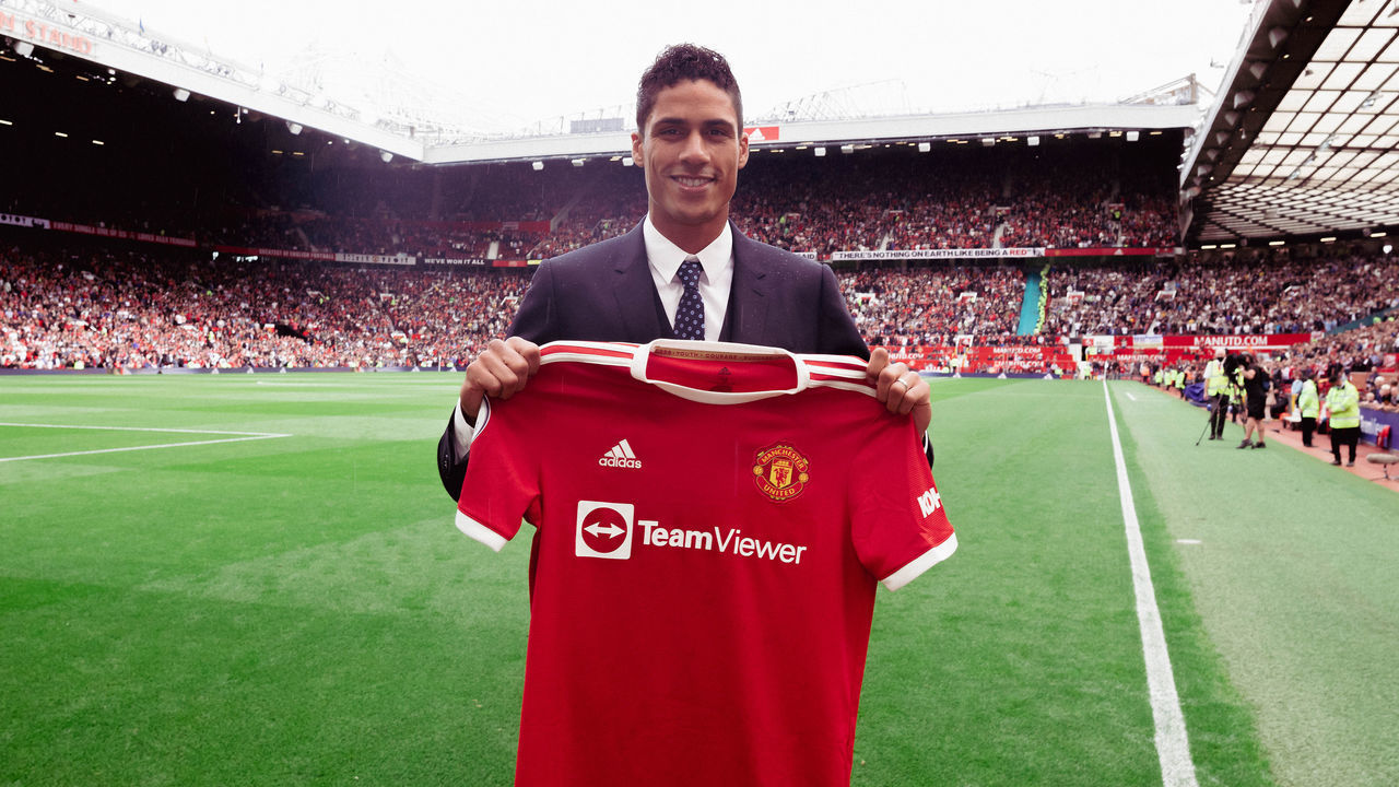 MANCHESTER, ENGLAND - AUGUST 14: Raphael Varane of Manchester Unite poses with a shirt as he is unveiled prior to the Premier League match between Manchester United and Leeds United at Old Trafford on August 14, 2021 in Manchester, England.