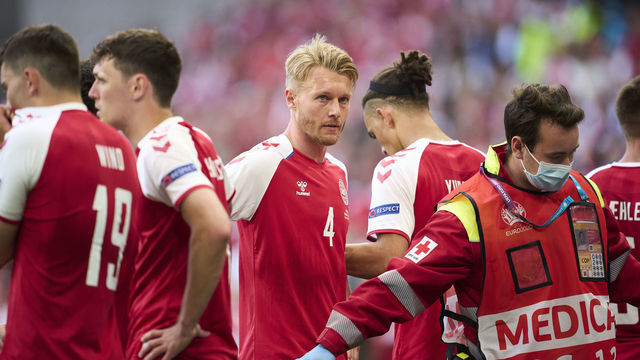 COPENHAGEN, DENMARK - JUNE 12: Danish captain Simon Kjar of Denmark stands near Christian Eriksen of Denmark when he receives medical treatment during the UEFA EURO 2020 Group B match between Denmark and Finland at Parken Stadium on June 12, 2021 in Copenhagen, Denmark.