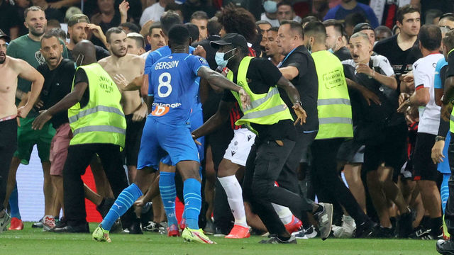 Security try to prevent fans as they invade the pitch during the French L1 football match between OGC Nice and Olympique de Marseille (OM) at the Allianz Riviera stadium in Nice, southern France on August 22, 2021. - The French Ligue 1 game between Nice and Marseille was halted on August 22, 2021, when fans of the home side invaded the pitch and angrily confronted opposing player Dimitri Payet. An AFP journalist at the game said trouble flared in the 75th minute when Marseille star Payet, who had been targeted by plastic bottles every time he took a corner, lobbed one back into the stands.