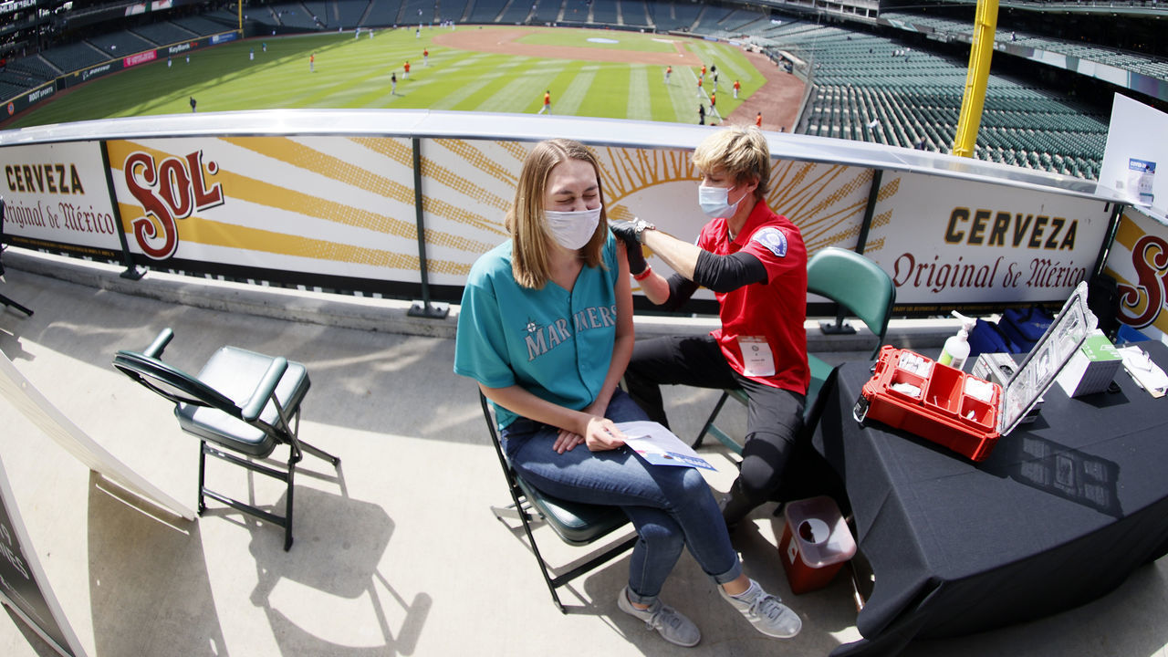 SEATTLE, WASHINGTON - MAY 05: Aeryal Thomsen of Lake Stevens, Wa. receives her COVID-19 vaccination from Kristine Gill, with the Seattle Fire Department’s Mobile Vaccination Teams, before the game between the Seattle Mariners and the Baltimore Orioles at T-Mobile Park on May 05, 2021 in Seattle, Washington.
