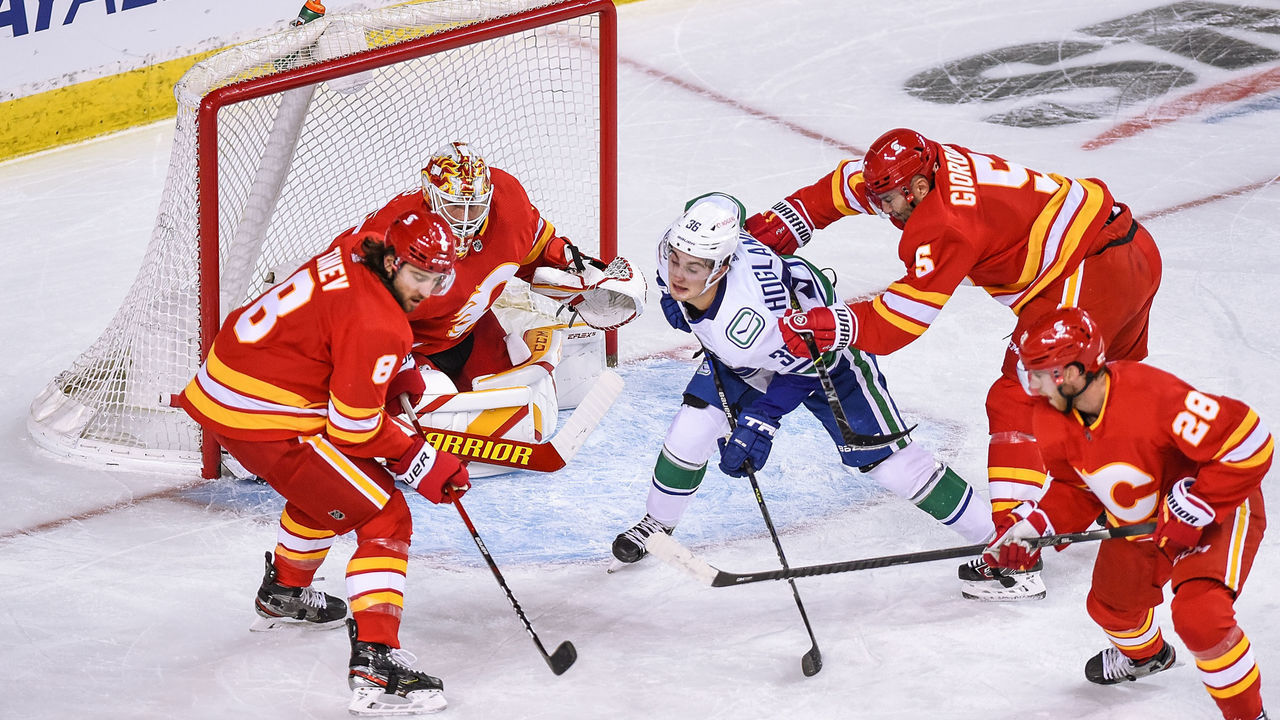 CALGARY, AB - JANUARY 16: Calgary Flames Defenceman Christopher Tanev (8) tries to clear the puck from in front of Calgary Flames Goalie Jacob Markstrom (25) while Vancouver Canucks Left Wing Nils Hoglander (36) takes a crosscheck from Calgary Flames Defenceman Mark Giordano (5) during the first period of an NHL game where the Calgary Flames hosted the Vancouver Canucks on January 16, 2021, at the Scotiabank Saddledome in Calgary, AB.