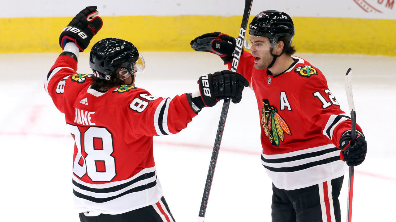 CHICAGO, IL - MARCH 05: Chicago Blackhawks left wing Alex DeBrincat (12) celebrates with Chicago Blackhawks right wing Patrick Kane (88) and teammates after scoring a goal in action during a game between the Chicago Blackhawks and the Tampa Bay Lightning at the United Center on March 5, 2021 in Chicago, Illinois.