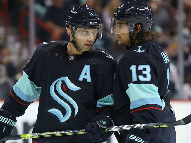 SPOKANE, WASHINGTON - SEPTEMBER 26: Mark Giordano #5 and Brandon Tanev #13 of the Seattle Kraken talk in the second period against the Vancouver Canucks during a preseason game at Spokane Veterans Memorial Arena on September 26, 2021 in Spokane, Washington.