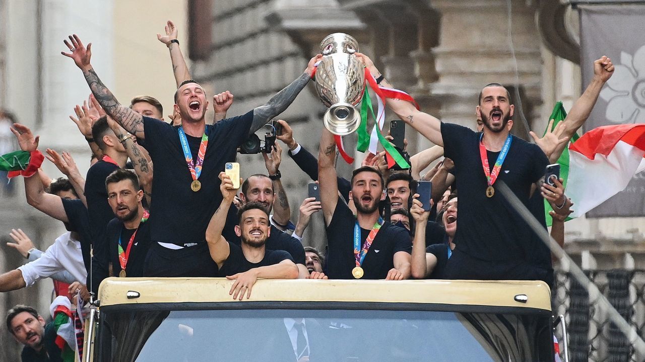 TOPSHOT - Players of Italy's national football team parade with the UEFA EURO 2020 trophy on a double decker bus in Rome on July 12, 2021, a day after Italy won the UEFA EURO 2020 final football match between Italy and England.