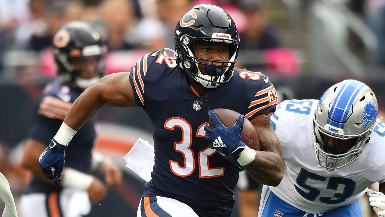 CHICAGO, ILLINOIS - OCTOBER 03: David Montgomery #32 of the Chicago Bears runs with the ball away from Charles Harris #53 of the Detroit Lions in the first half at Soldier Field on October 03, 2021 in Chicago, Illinois.