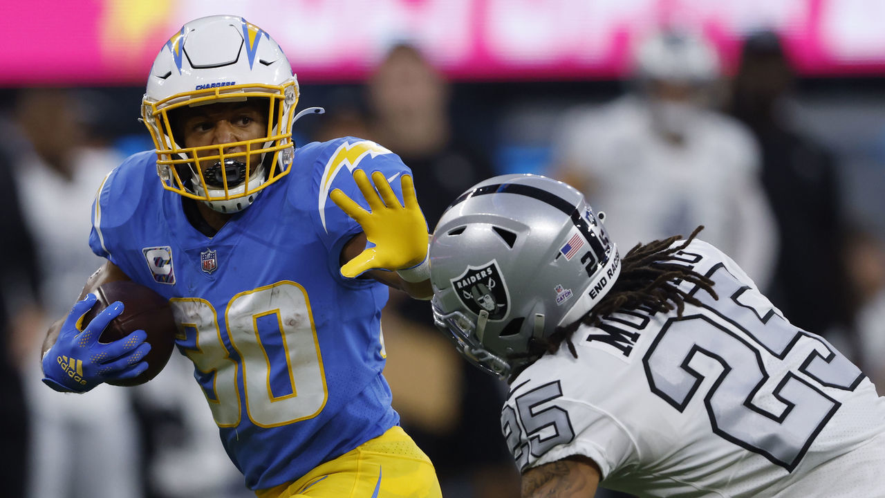 INGLEWOOD, CALIFORNIA - OCTOBER 04: Running back Austin Ekeler #30 of the Los Angeles Chargers rushes past safety Trevon Moehrig #25 of the Las Vegas Raiders during the first half at SoFi Stadium on October 4, 2021 in Inglewood, California.