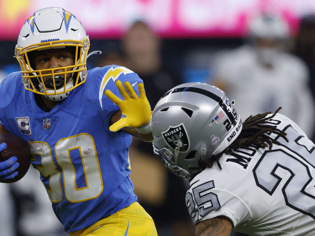 INGLEWOOD, CALIFORNIA - OCTOBER 04: Running back Austin Ekeler #30 of the Los Angeles Chargers rushes past safety Trevon Moehrig #25 of the Las Vegas Raiders during the first half at SoFi Stadium on October 4, 2021 in Inglewood, California.