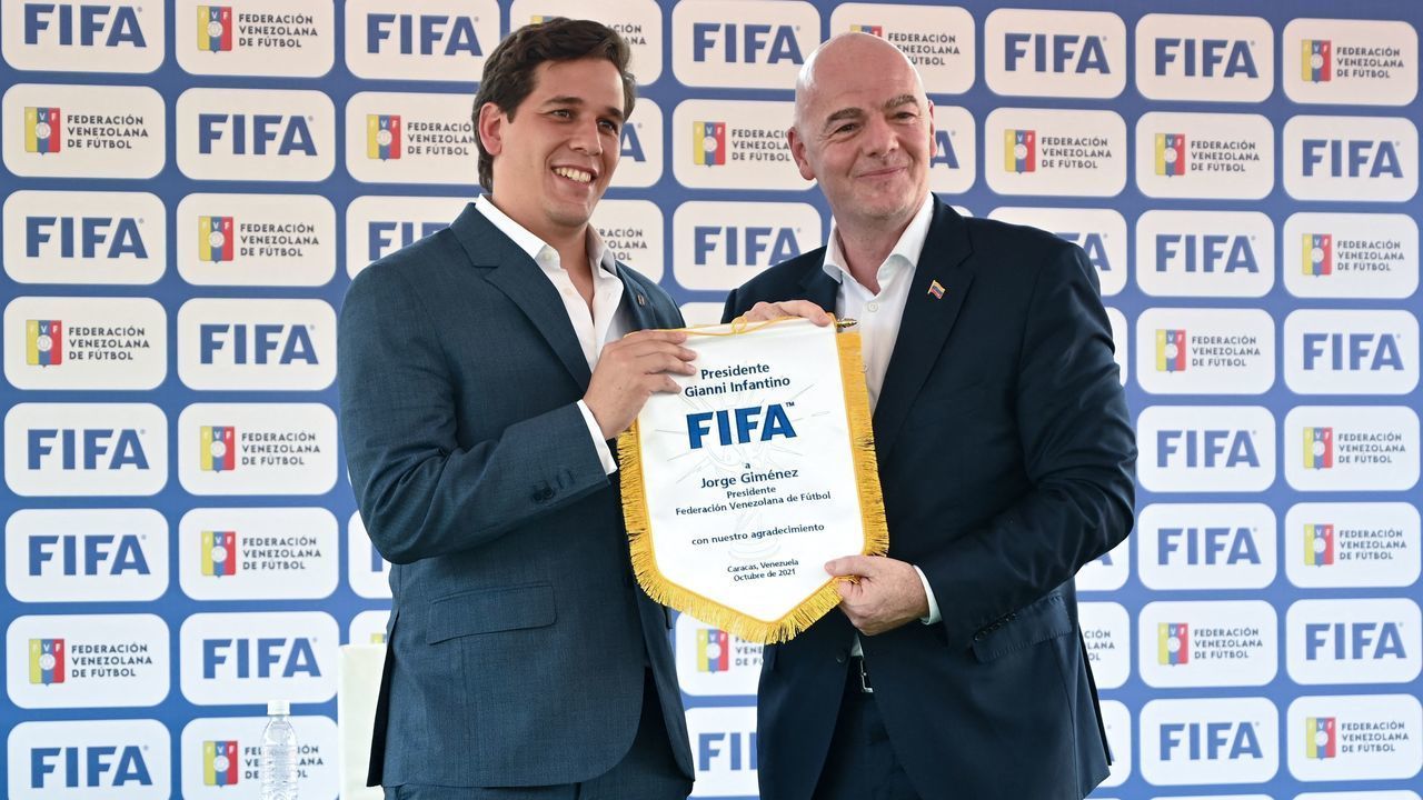 FIFA president Gianni Infantino (R) and the president of the Venezuelan Football Federation (FVF) Jorge Gimenez hold a flag at the Olympic stadium of the Central University of Venezuela, in Caracas on October 15, 2021.