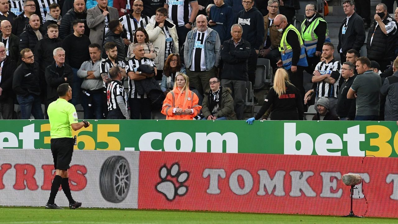 English referee Andre Marriner (L) goes over to seek information as a medical emergency in the crowd stops play shortly before half time during the English Premier League football match between Newcastle United and Tottenham Hotspur at St James' Park in Newcastle-upon-Tyne, north east England on October 17, 2021. - RESTRICTED TO EDITORIAL USE. No use with unauthorized audio, video, data, fixture lists, club/league logos or 'live' services. Online in-match use limited to 120 images. An additional 40 images may be used in extra time. No video emulation. Social media in-match use limited to 120 images. An additional 40 images may be used in extra time. No use in betting publications, games or single club/league/player publications.