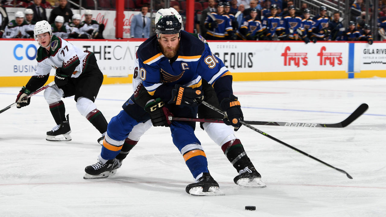 GLENDALE, ARIZONA - OCTOBER 18: Ryan O'Reilly #90 of the St Louis Blues defends the puck against Jakob Chychrun #6 of the Arizona Coyotes during the third period at Gila River Arena on October 18, 2021 in Glendale, Arizona. The Blues defeated the Coyotes 7-4.