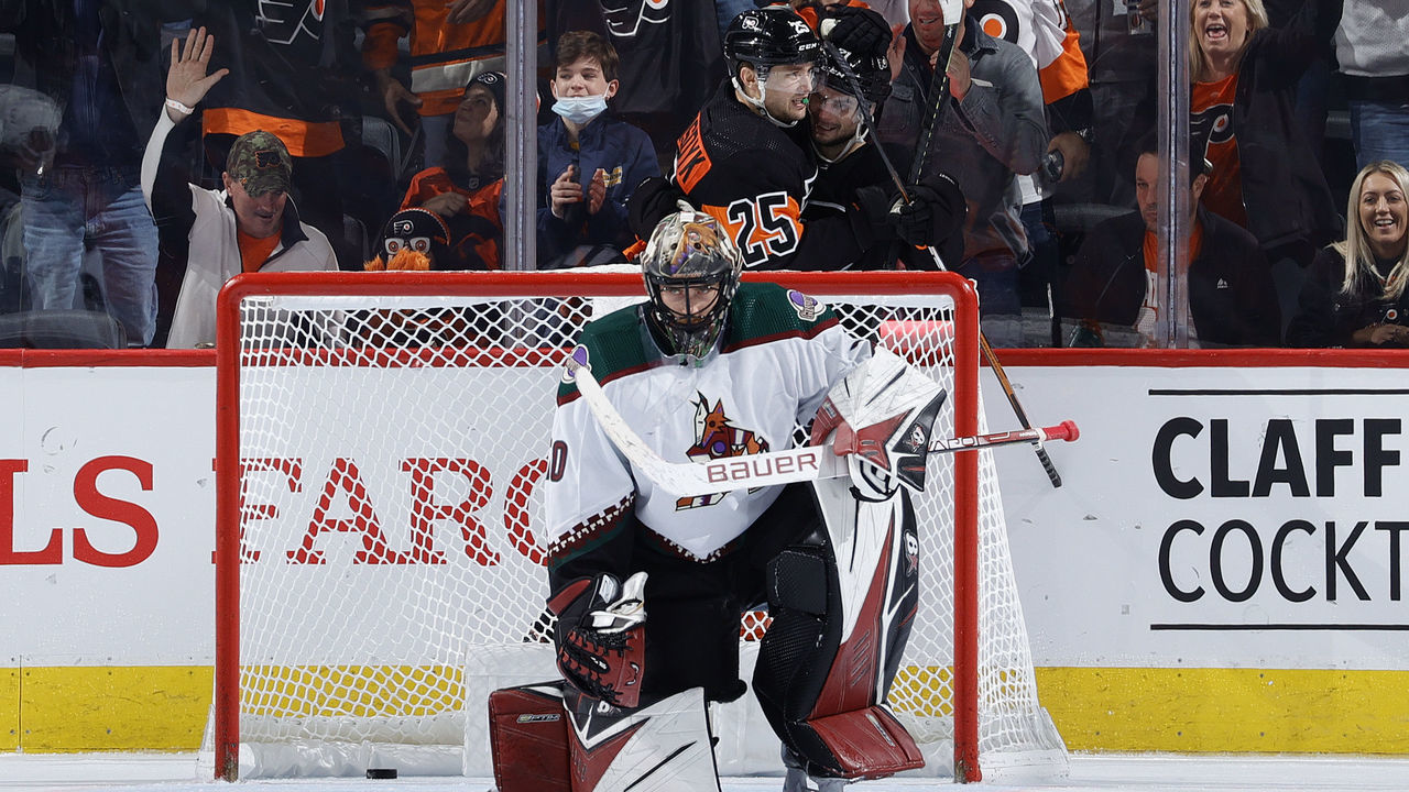 PHILADELPHIA, PENNSYLVANIA - NOVEMBER 02: Karel Vejmelka #70 of the Arizona Coyotes looks on as James van Riemsdyk #25 and Scott Laughton #21 of the Philadelphia Flyers celebrate a goal by Laughton during the third period at Wells Fargo Center on November 02, 2021 in Philadelphia, Pennsylvania.
